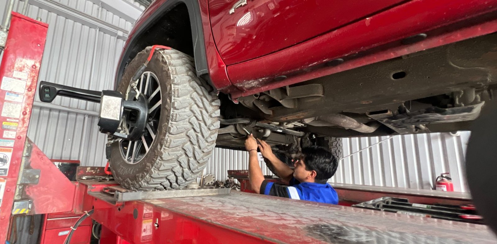 Técnico de Llantas y Servicio Salinas alineando una pickup en la rampa de alineación