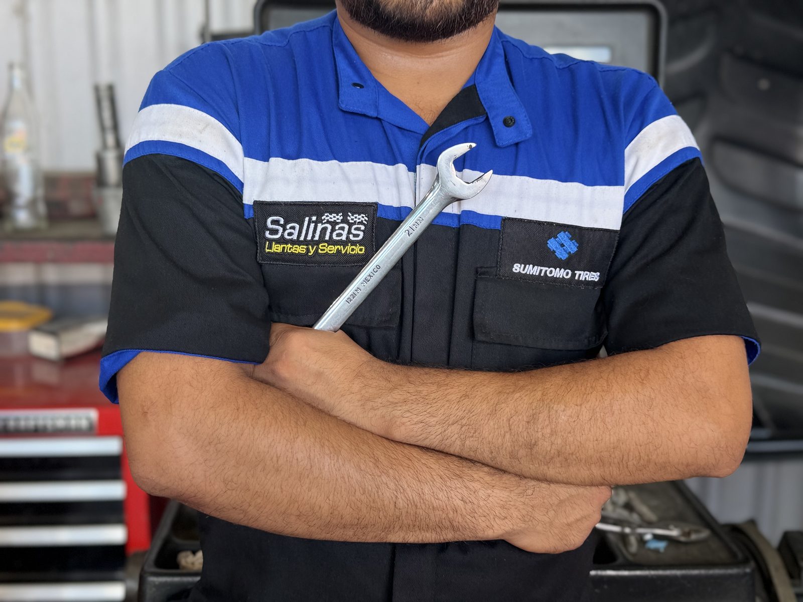 Técnico de Llantas y Servicio Salinas con uniforme y llave en el taller
